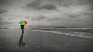 Person on beach holding umbrella on dark day