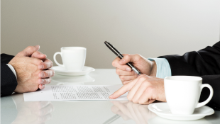 Two businessmen across from table with contracts