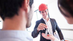 Construction worker handing keys to people